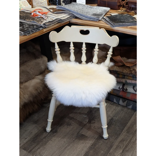 White painted wooden chair with a fluffy white merino sheepskin chair pad for cozy seating comfort