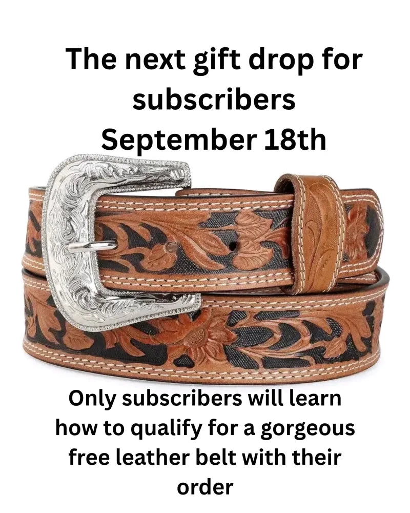 A brown leather belt with intricate floral tooling and a silver-toned buckle with engraved patterns