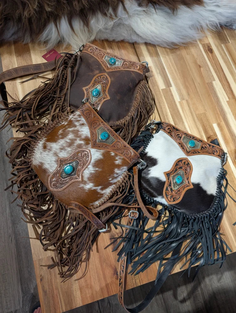 Three mojave tassel bags in rich hunter leather with cowhide patterns flowing fringe and turquoise stone accents