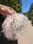 Light pink sheepskin pom pom with curly white fur and pink highlights by Angus Oliver