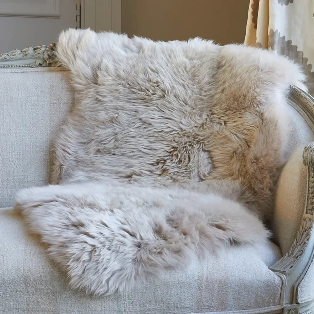 Cream-colored merino sheepskin cushion cover with cotton backs draped over an ornate armchair for cozy style