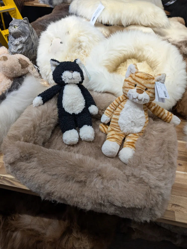 Cozy black and white plush cat on sheepskin pet bed