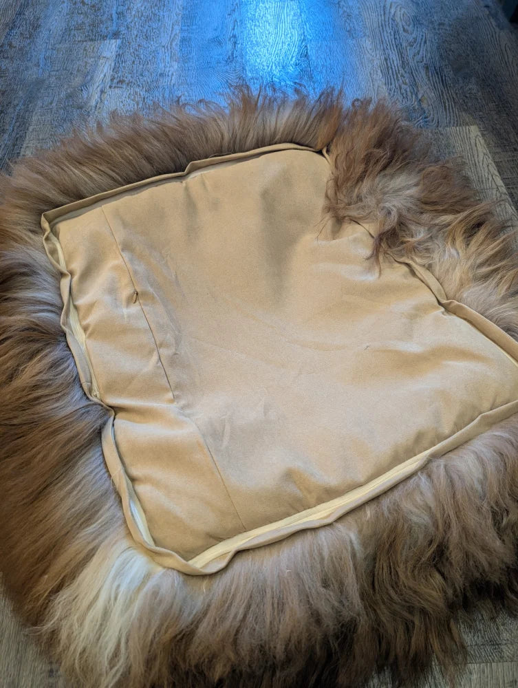Cozy highland sheepskin pet bed with cream fur throw and brown accents