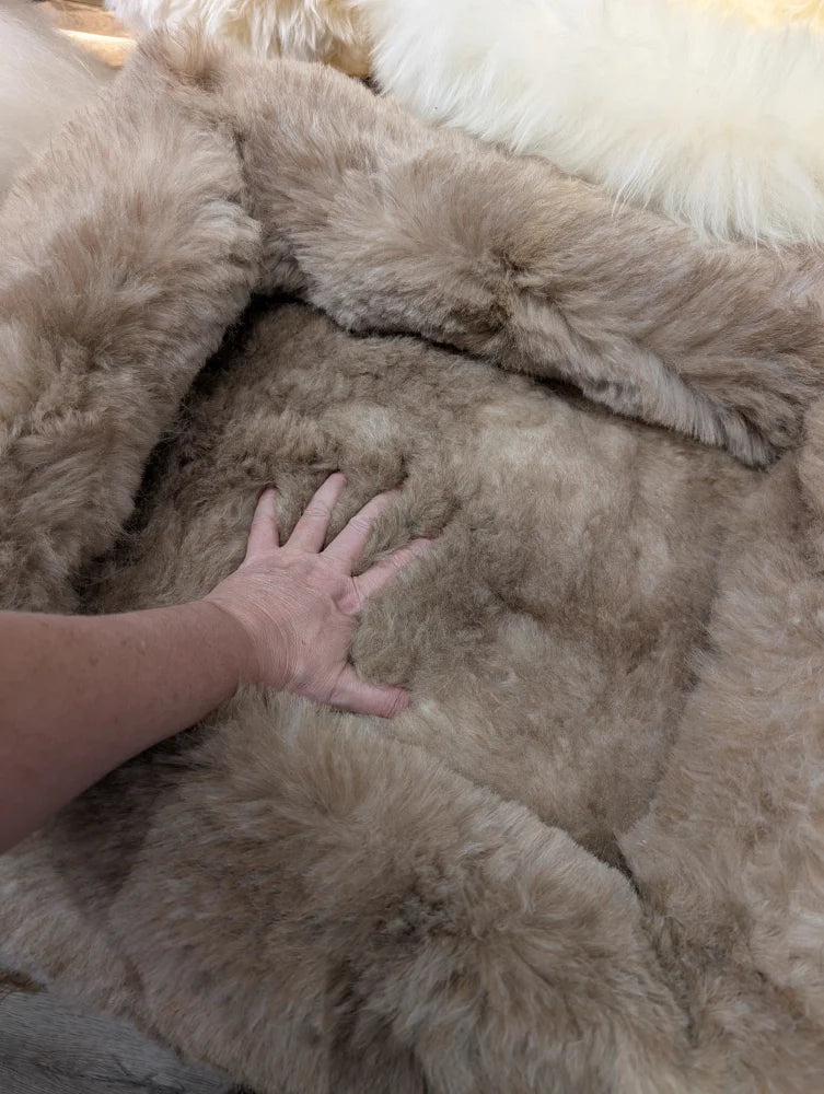 Cozy beige faux fur sheepskin pet bed with fringed plush edges