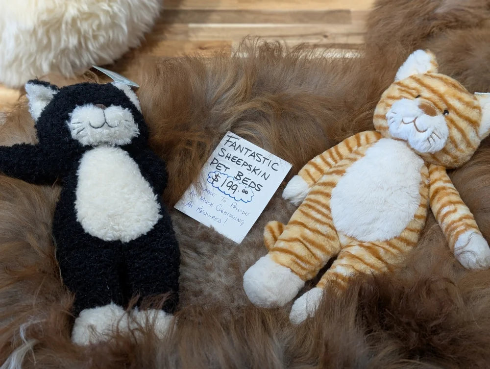 Cozy black and white cat plush on sheepskin pet bed