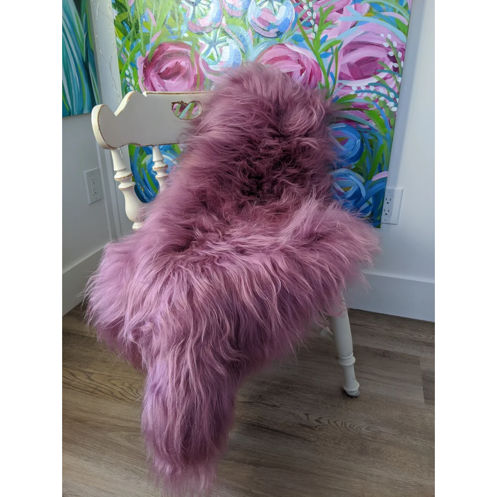 Cozy pink Icelandic sheepskin throw on white chair with floral art