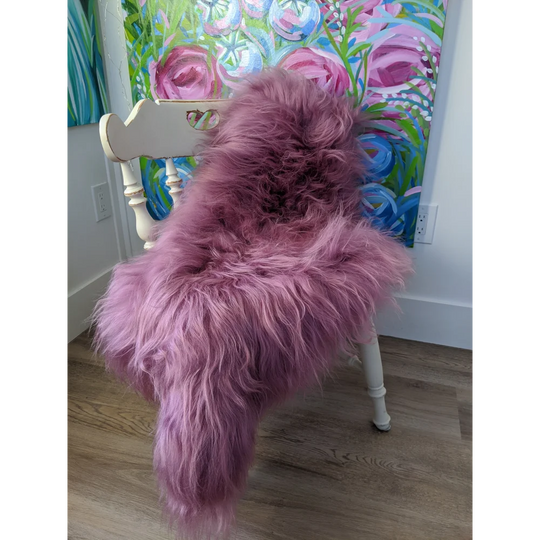 Cozy pink Icelandic sheepskin throw on white chair with floral art