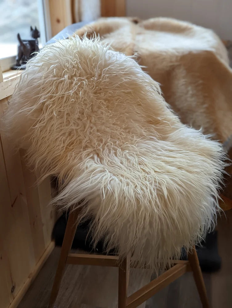 Cream-colored icelandic sheepskins long wool sheepskin throw draped over wooden chair for cozy decor