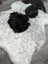 A large soft spotted icelandic sheepskin rug in white and black with curly wool and natural shape