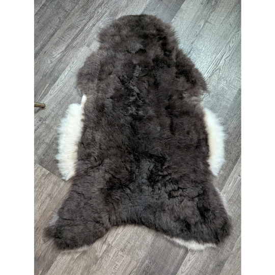 A large soft blacky icelandic sheepskin rug with dark gray short wool and a white underfur border
