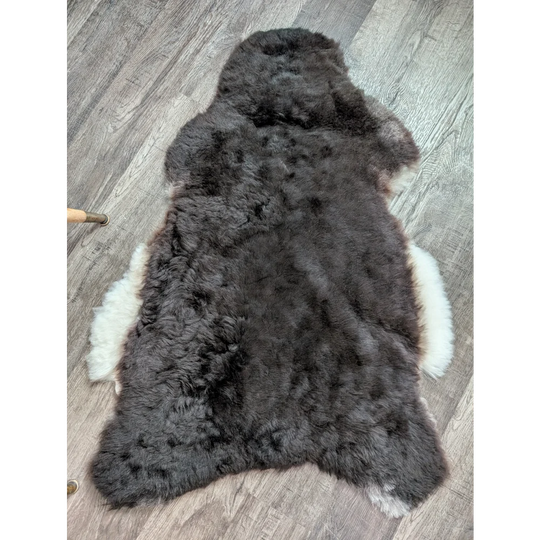 Plush large dark gray and white icelandic sheepskin rug with soft fluffy short wool texture perfect for cozy spaces