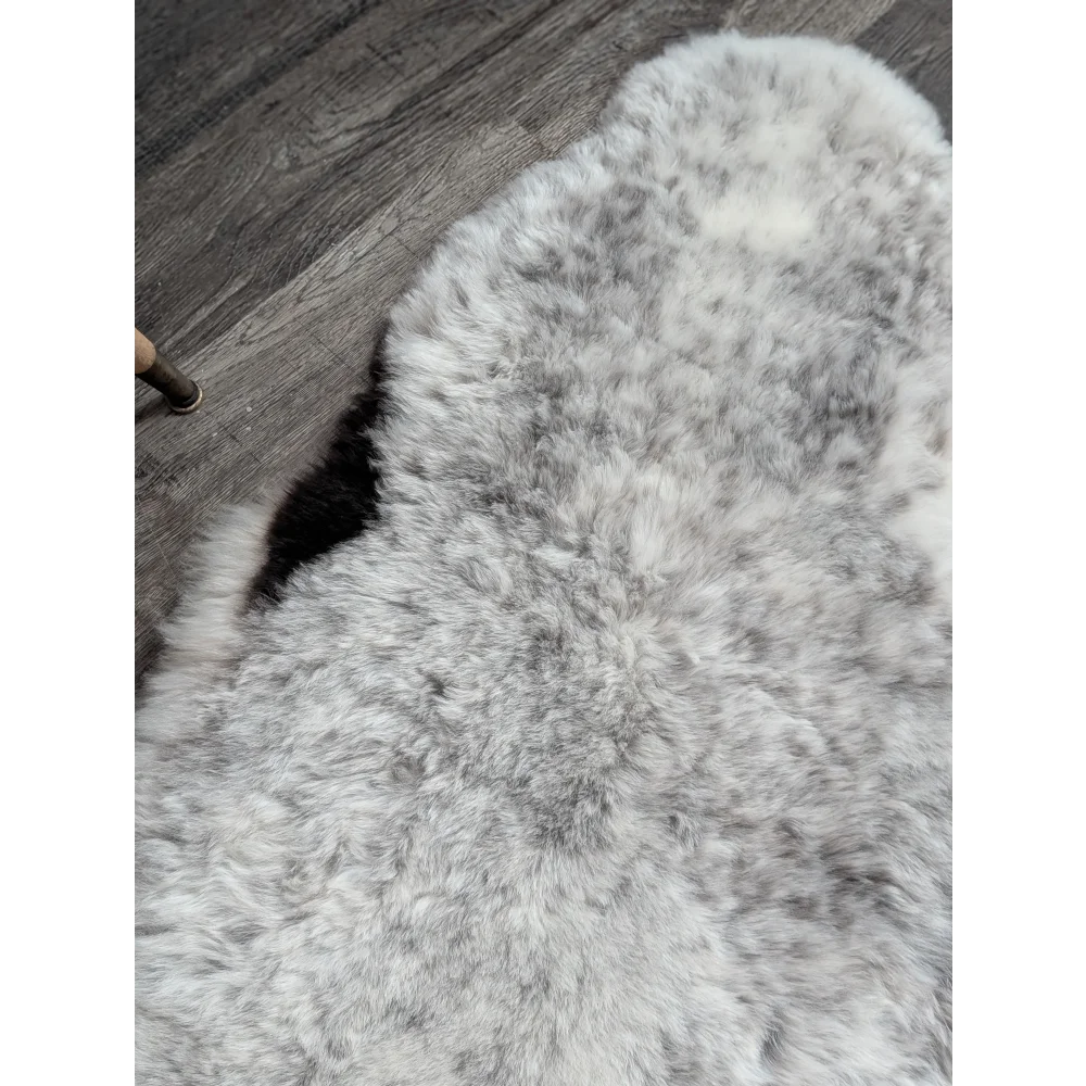 A plush irregular gray spotted icelandic sheepskin rug with soft fluffy texture and natural shade variations