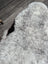A plush irregular gray spotted icelandic sheepskin rug with soft fluffy texture and natural shade variations
