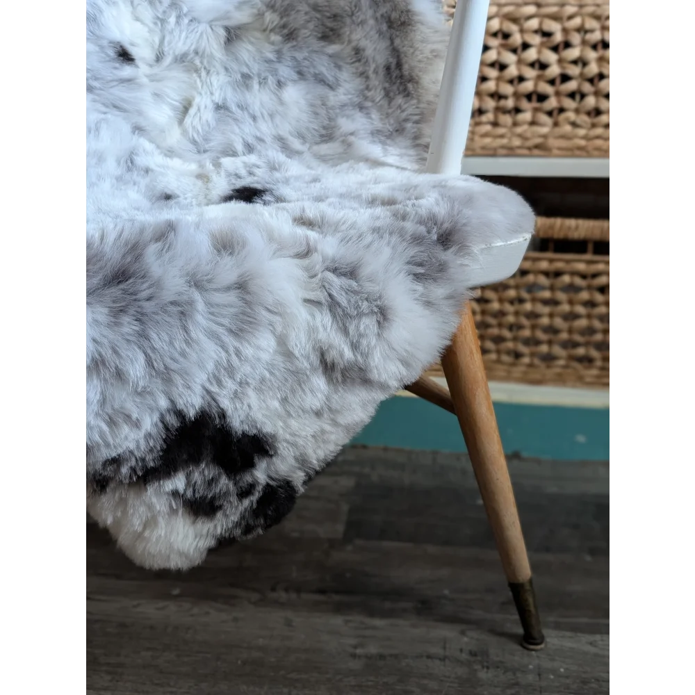 A large soft spotted icelandic sheepskin rug with natural white and gray fur texture perfect for cozy decor