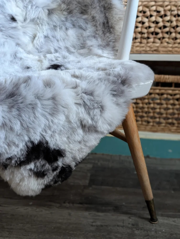 A large soft spotted icelandic sheepskin rug with natural white and gray fur texture perfect for cozy decor
