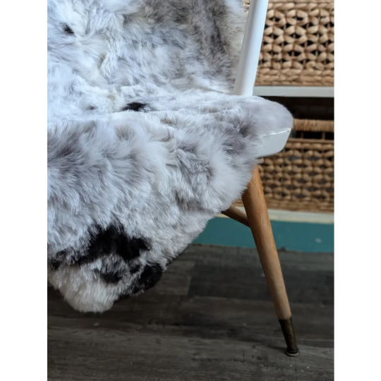 A large soft spotted icelandic sheepskin rug with natural white and gray fur texture perfect for cozy decor