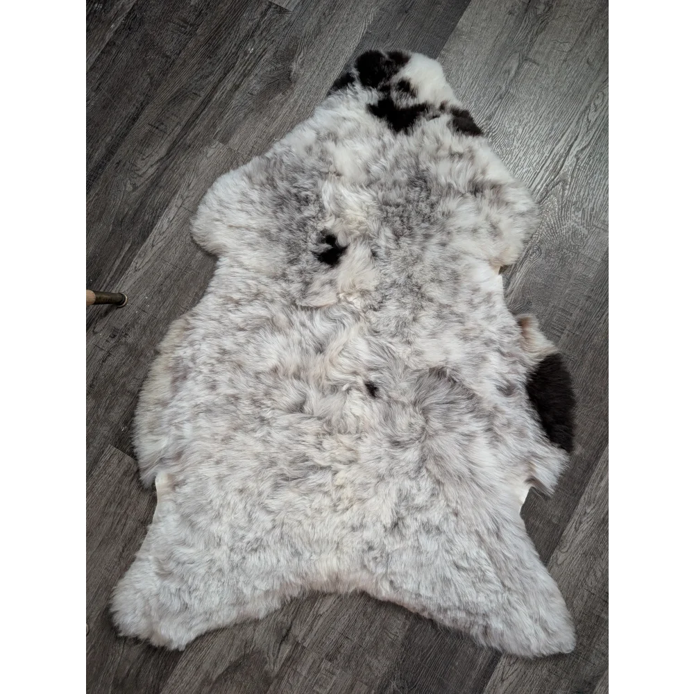 A large soft spotted icelandic sheepskin rug with natural white and black wool texture perfect for cozy spaces