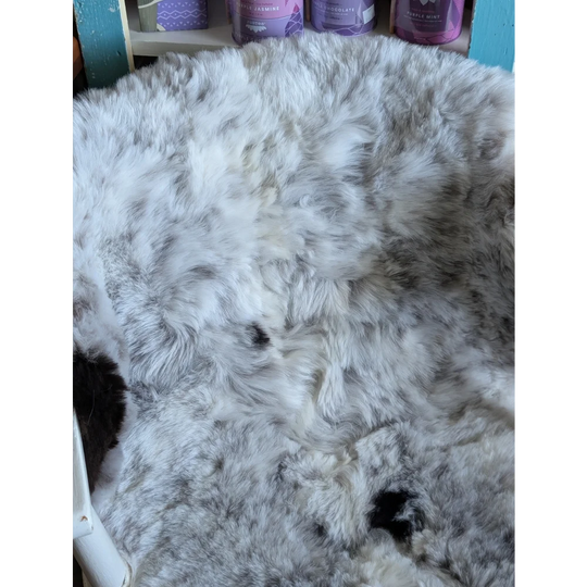 A plush large soft medium spotted icelandic sheepskin rug in gray and white with a fluffy textured surface