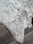 A plush gray and white large soft spotted icelandic sheepskin rug made of short wool with a fluffy texture