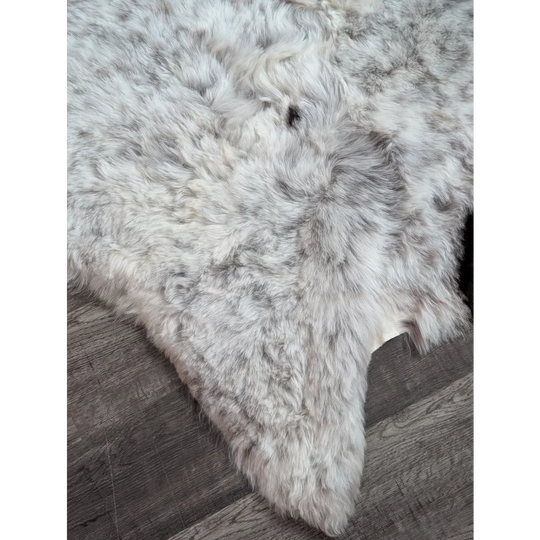 A plush gray and white large soft spotted icelandic sheepskin rug made of short wool with a fluffy texture