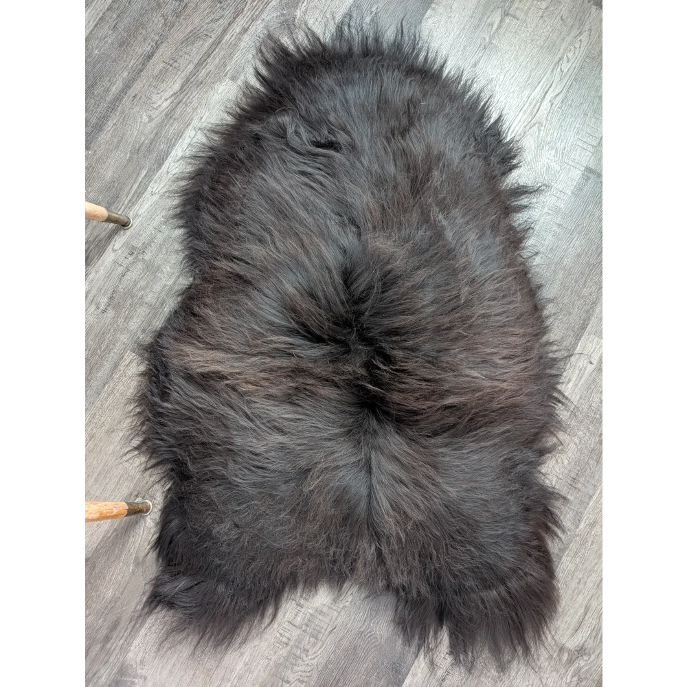 A plush dark gray icelandic sheepskin rug with thick long wool and natural edges perfect for cozy spaces