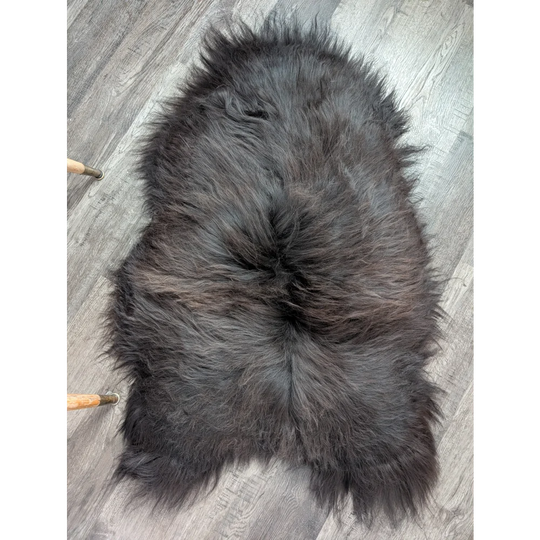 A plush dark gray icelandic sheepskin rug with thick long wool and natural edges perfect for cozy spaces