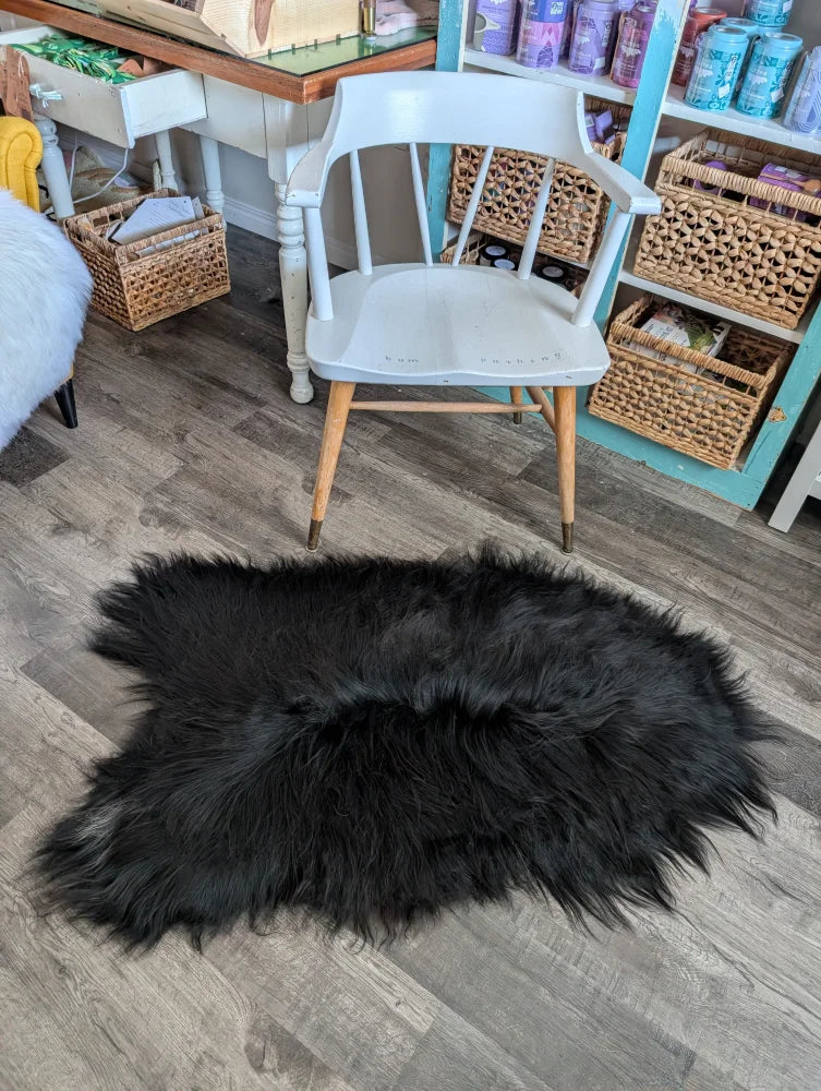 Black fluffy icelandic sheepskin rug with natural shape and long wool soft dense fur in natural blacky color