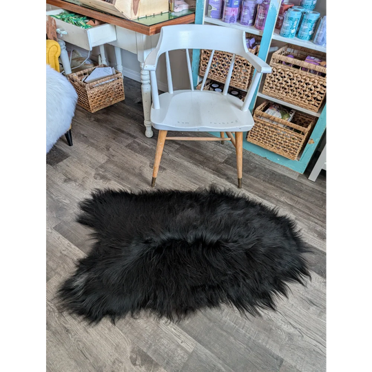 Black fluffy icelandic sheepskin rug with natural shape and long wool soft dense fur in natural blacky color