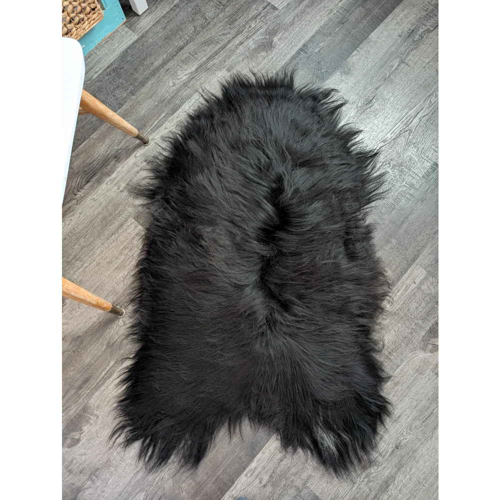 Large soft icelandic sheepskin rug in natural black with long wool and fluffy irregular edges for cozy decor