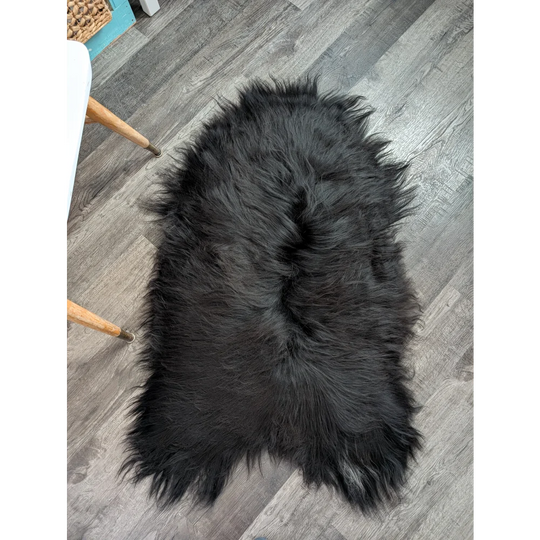 Large soft icelandic sheepskin rug in natural black with long wool and fluffy irregular edges for cozy decor