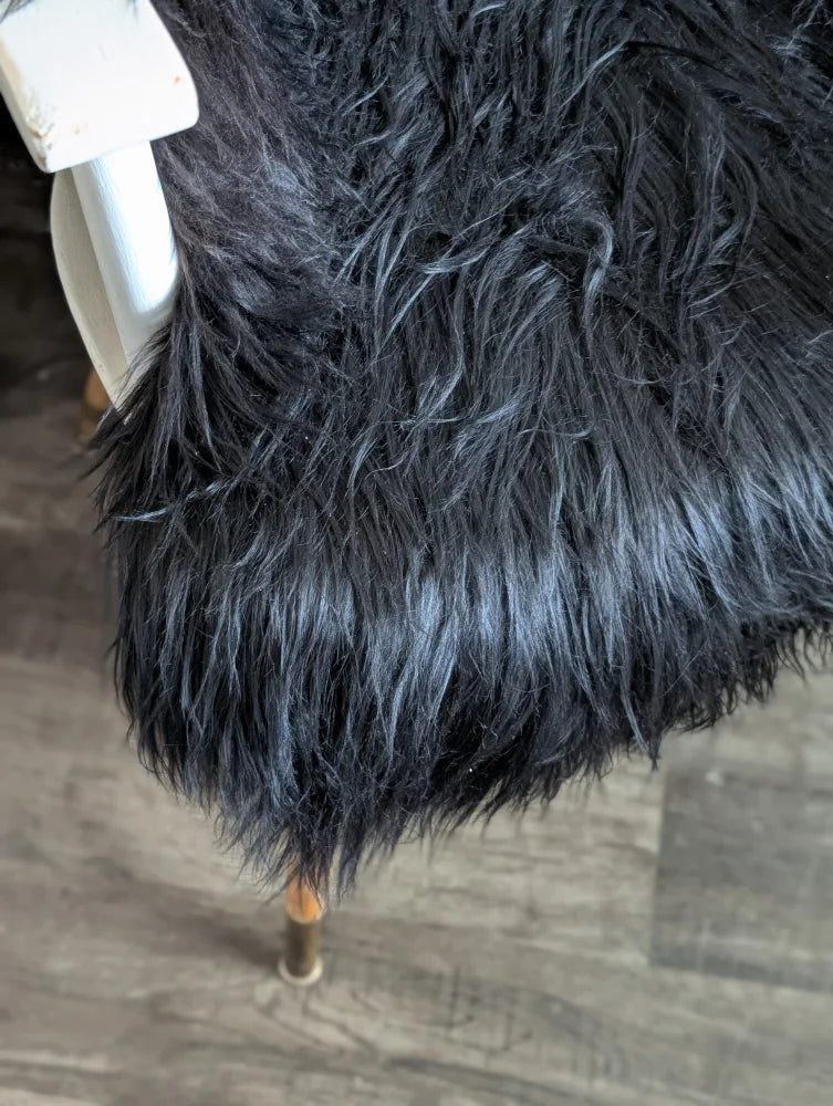 Black faux fur chair cover with plush shaggy texture made of soft wool icelandic long wool sheepskin