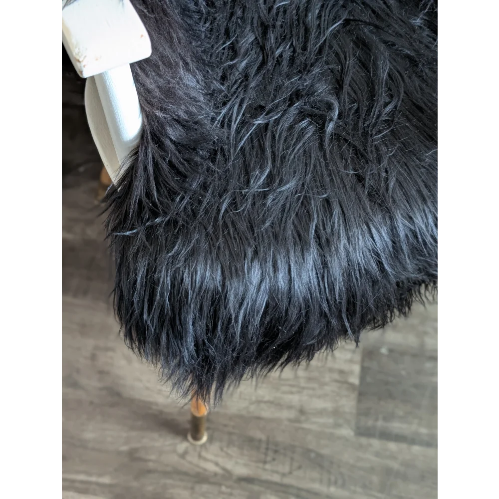 Black faux fur chair cover with plush shaggy texture made of soft wool icelandic long wool sheepskin