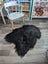 Black fluffy icelandic sheepskin rug with long wool in natural irregular shape soft dense fur for cozy decor