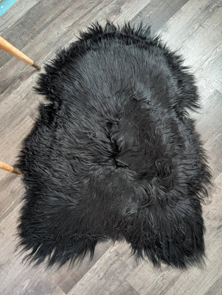 Black fluffy icelandic sheepskin rug with natural edge and long wool ideal for cozy home decor use