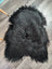 Black fluffy icelandic sheepskin rug with natural edge and long wool ideal for cozy home decor use