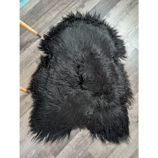Black fluffy icelandic sheepskin rug with natural edge and long wool ideal for cozy home decor use