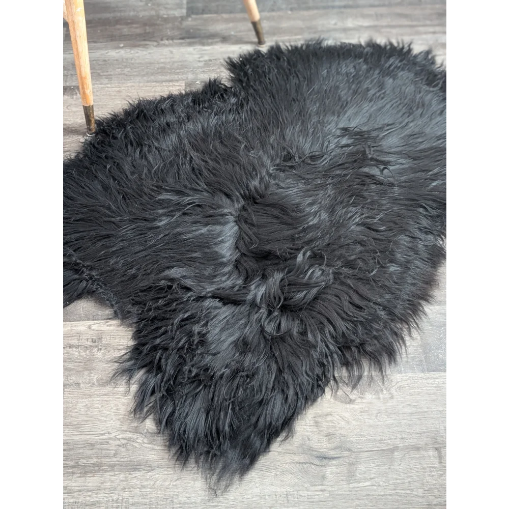 Black fluffy large soft icelandic sheepskin rug with long wool and natural irregular shape in black color