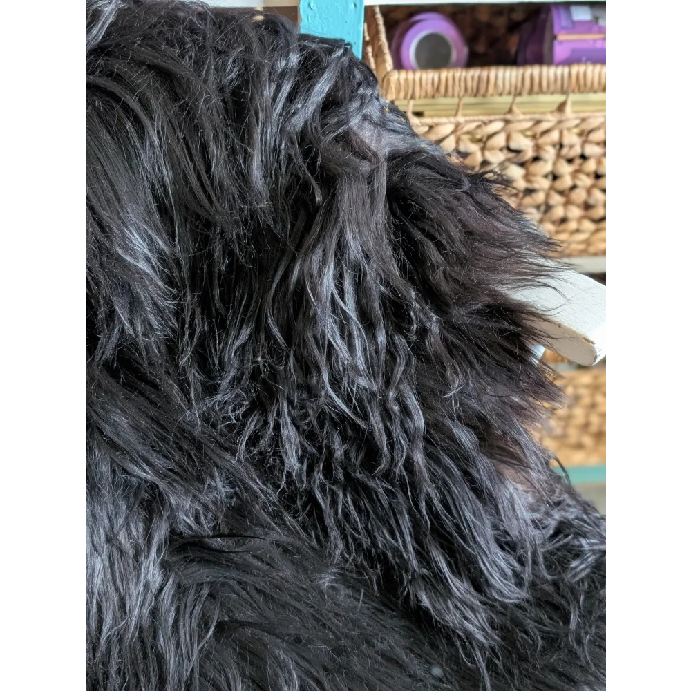 A large soft icelandic sheepskin throw in natural black with long wool and plush textured surface ideal for cozy use