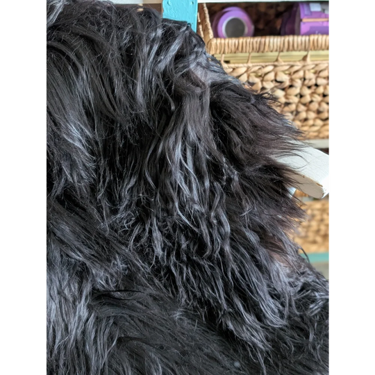 A large soft icelandic sheepskin throw in natural black with long wool and plush textured surface ideal for cozy use