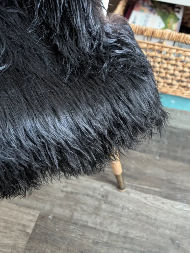 Black faux fur chair with plush shaggy texture and wooden legs made from long wool icelandic sheepskin