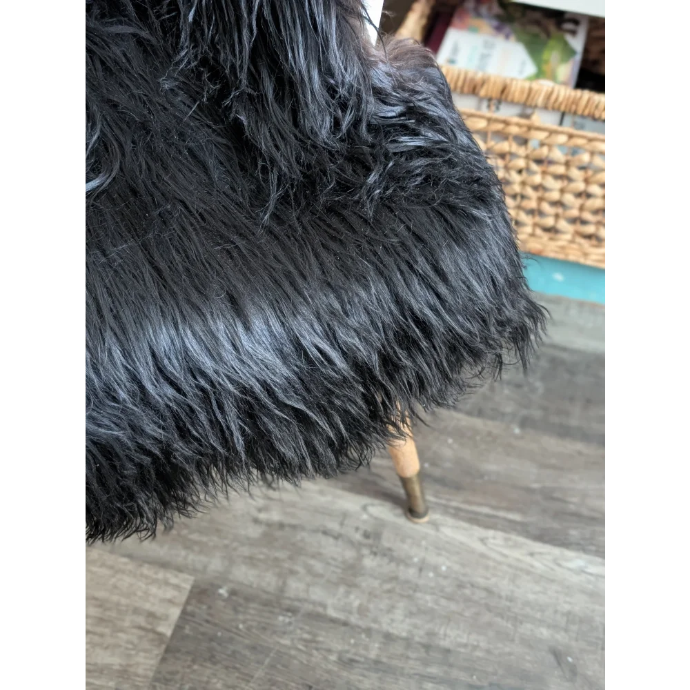 Black faux fur chair with plush shaggy texture and wooden legs made from long wool icelandic sheepskin