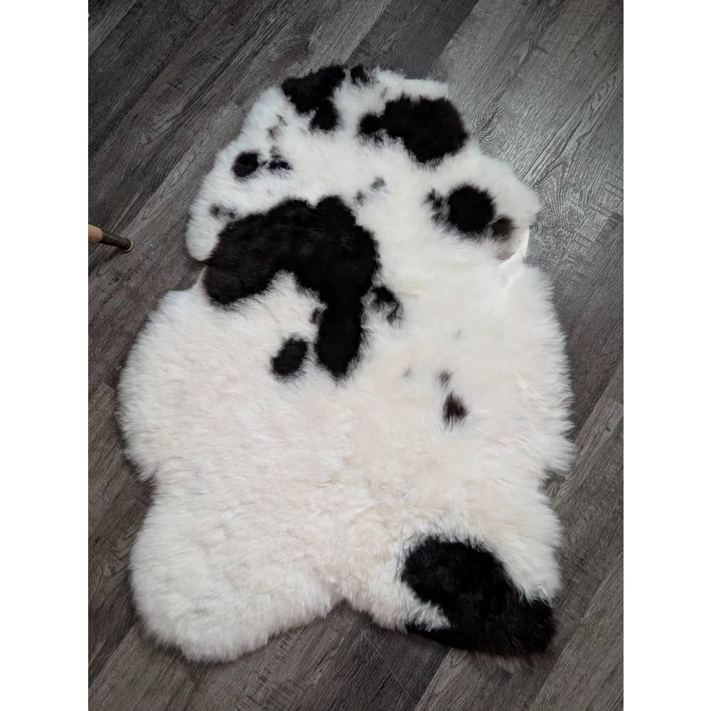 A plush white and black medium spotted icelandic sheepskin rug with soft fluffy texture perfect for cozy spaces