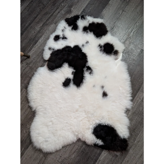 A plush white and black medium spotted icelandic sheepskin rug with soft fluffy texture perfect for cozy spaces