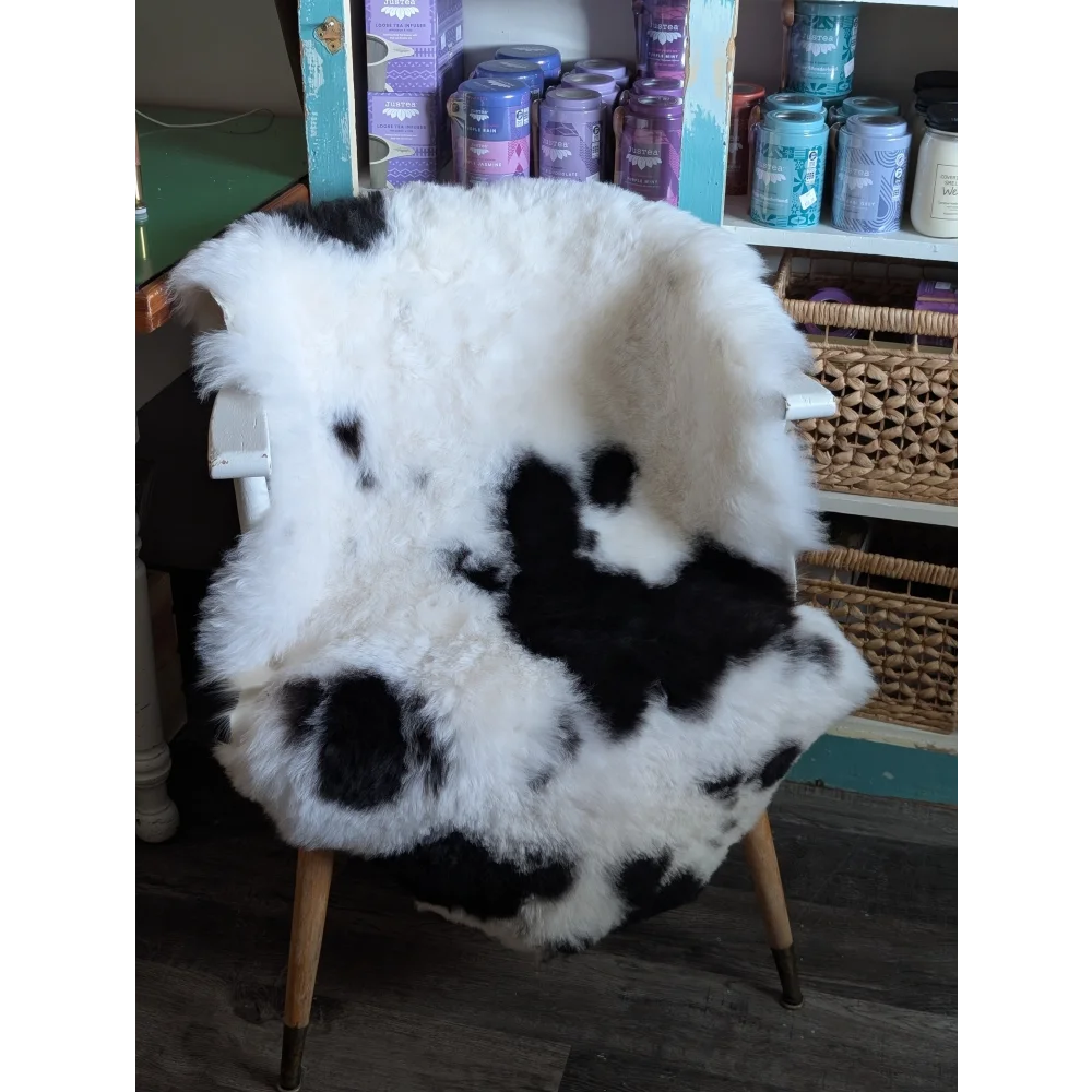 A plush black and white spotted icelandic sheepskin rug draped over a chair for cozy home decor
