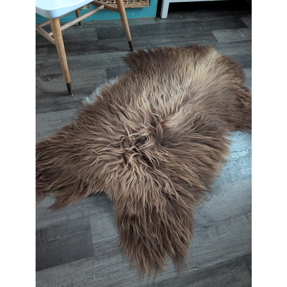 A plush bronze long wool icelandic sheepskin rug with soft fur on a dark wood floor perfect for cozy spaces