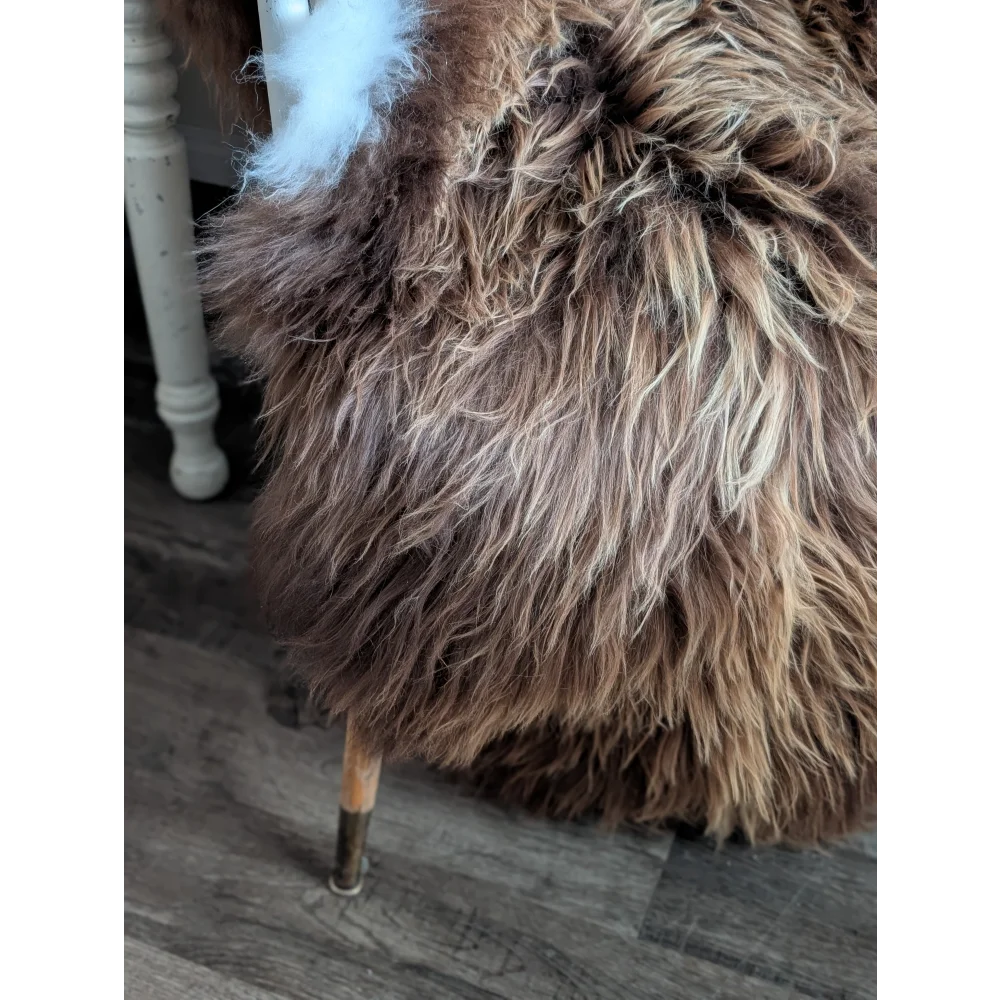A plush long wool icelandic brown and cream sheepskin-covered stool with wooden legs from luv44 massive bronze collection