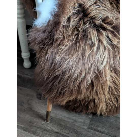 A plush long wool icelandic brown and cream sheepskin-covered stool with wooden legs from luv44 massive bronze collection