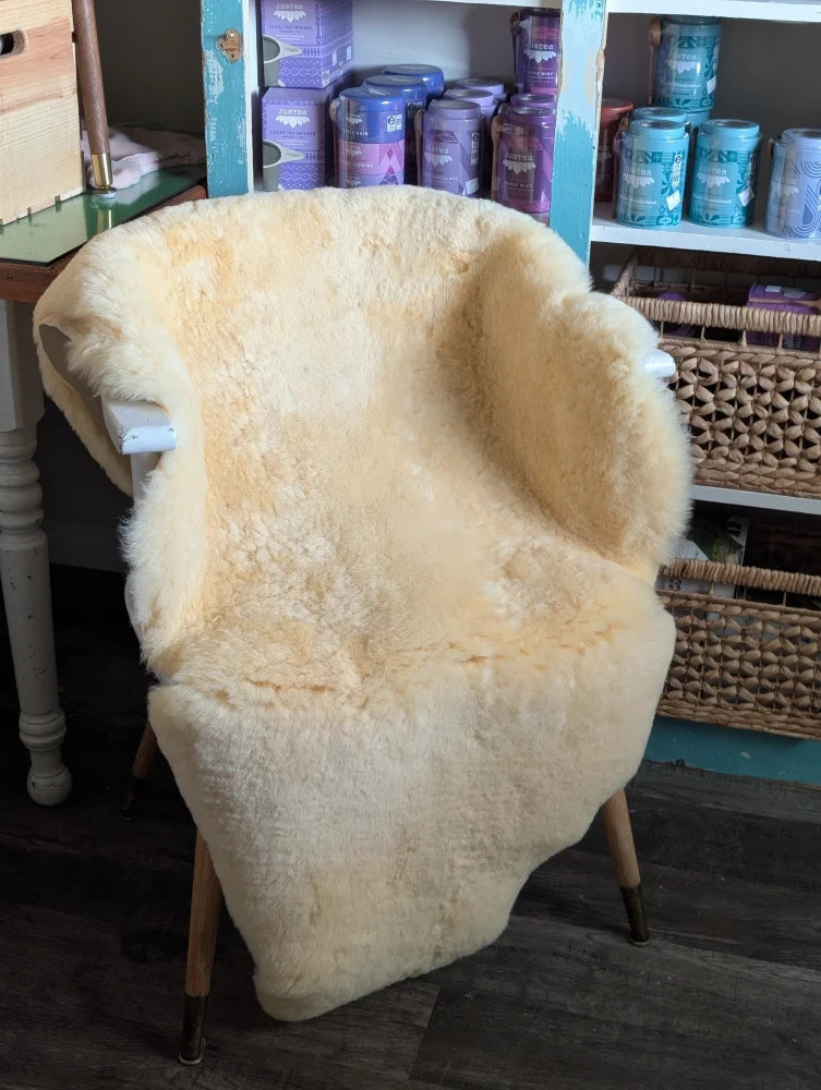 Cream-colored medical sheepskin cover draped over wooden armchair by angus oliver for comfort and style