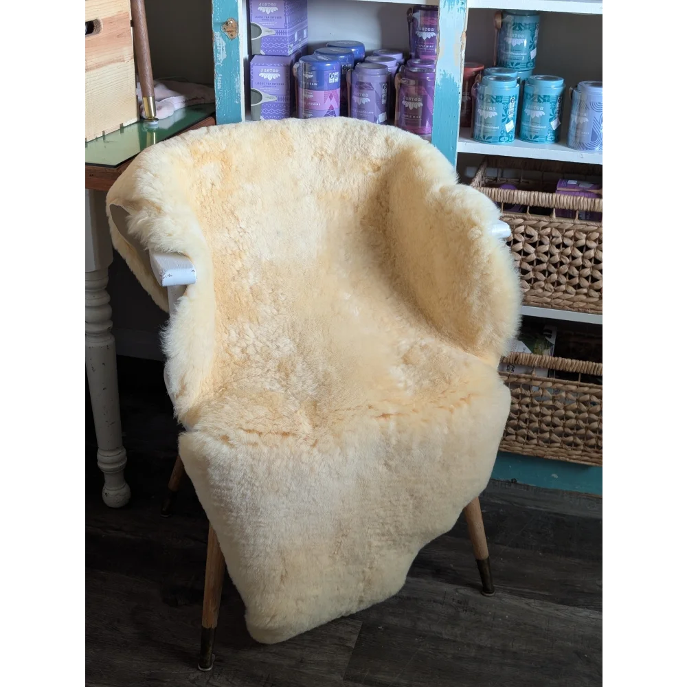 Cream-colored medical sheepskin cover draped over wooden armchair by angus oliver for comfort and style