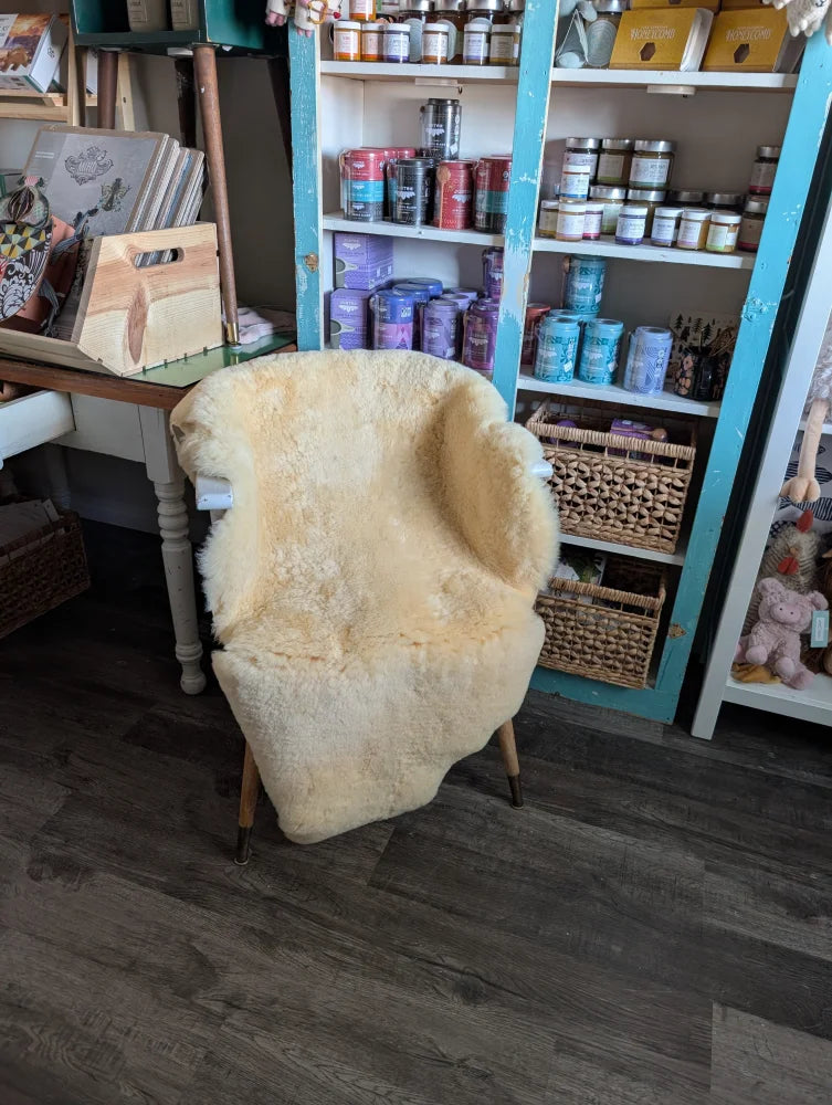 Cream-colored medical sheepskin washable chair cover draped over wooden armchair from angus oliver sheepskin rugs